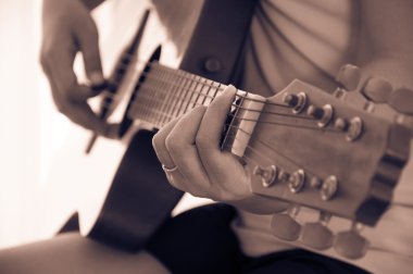 Kadın akustik gitar çalıyor.