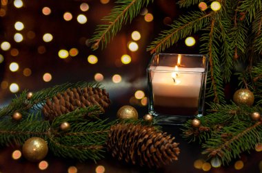 Noel 'de güzel dallar ve koniler, koyu bir arka planda yanan bir mum. Noel dekoru