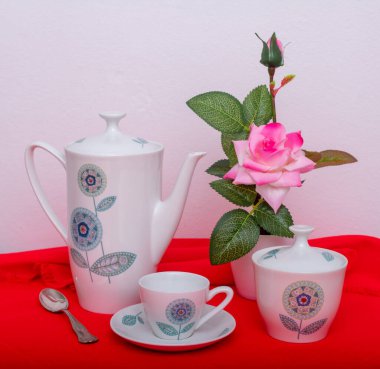 Çikolatalı kurabiye, bir fincan kahve, kahve makinesi, çaydanlık ve pembe çiçekli vazo..