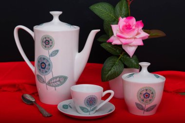 Çikolatalı kurabiye, bir fincan kahve, kahve makinesi, çaydanlık ve pembe çiçekli vazo..