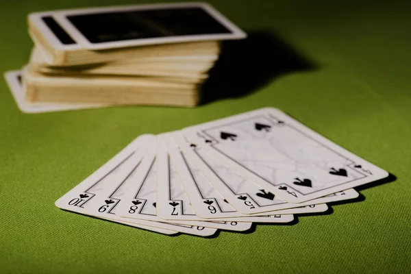 Used playing cards on green carpet — Stock Photo, Image