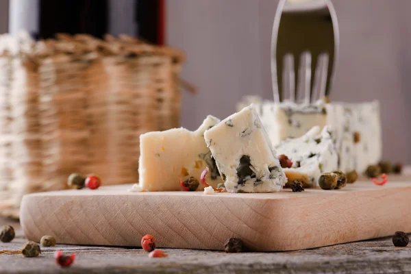 Stukje blauwe kaas op een houten bord met peper — Stockfoto