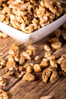 Birkaç ceviz ahşap tahta üzerinde beyaz kase çevresinde döktüm