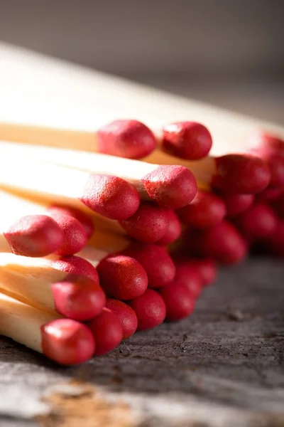 Un mucchio di fiammiferi con teste rosse su tavola di legno — Foto Stock