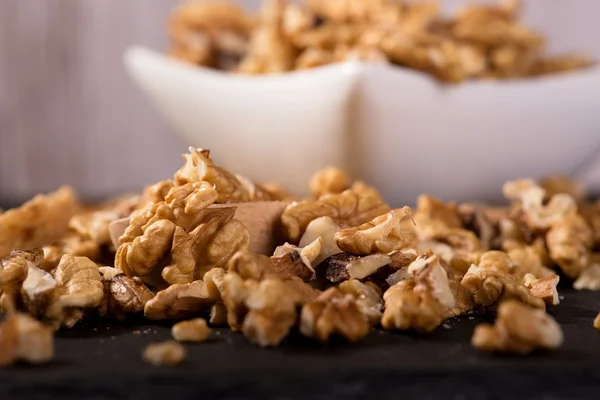 Nueces derramadas frente a cuenco blanco cuadrado — Foto de Stock