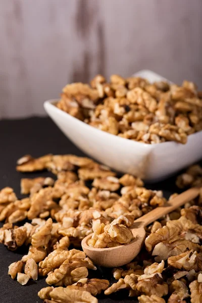 Spoon with walnuts which are too spilled around on slate — Stock Photo, Image