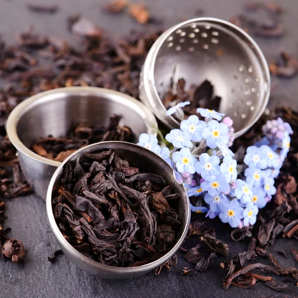 Filtro pieno di foglie di tè e fiori blu su ardesia — Foto Stock