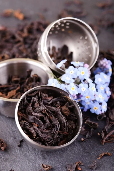 Colino da tè su pietra di ardesia nera con fiore blu — Foto Stock