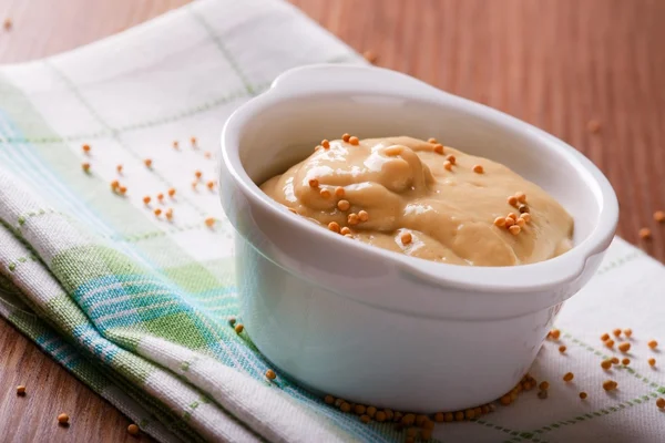 White bowl with mustard  and seeds on green towel — Stok fotoğraf