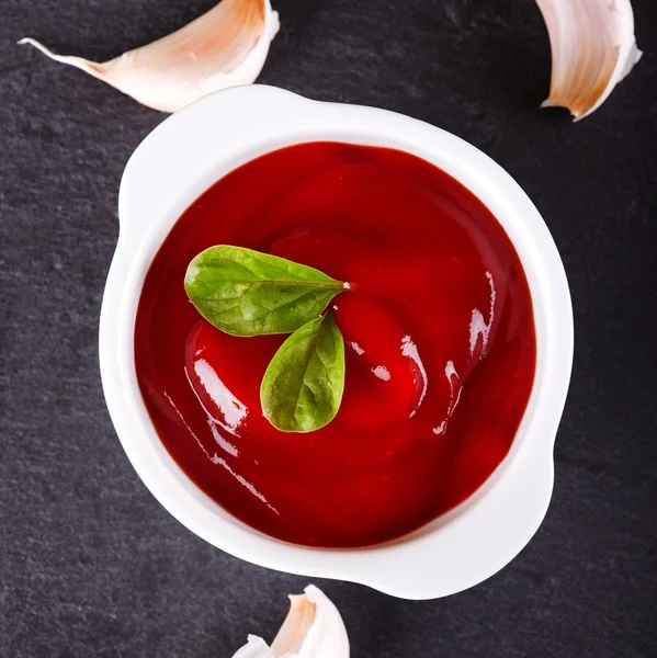 Top view on ketchup with garlic around on slate stone — Stok Foto