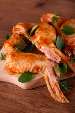 Ahşap tahta üzerinde otlar ile birkaç marine tavuk kanatları