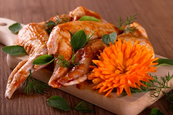 Tres alas de pollo marinadas con caléndula sobre tabla de madera — Foto de Stock