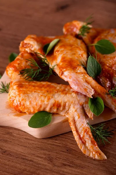 Ahşap tahta üzerinde otlar ile birkaç marine tavuk kanatları