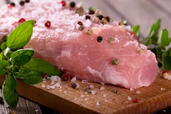 Деталь сырой свинины с солью и цветным перцем на доске — стоковое фото