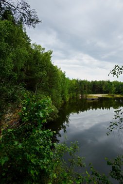 Bulutlu gökyüzü ile sular altında bir kum ocağı görüntüleyin