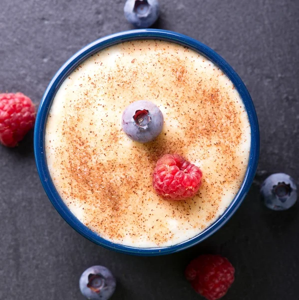 Top view on creamy dessert with cinnamon and summer berries — Stock Photo, Image