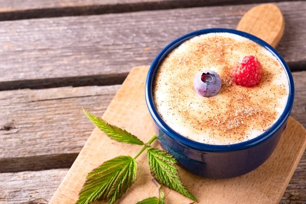 Blue bowl full of creamy dessert and with couple of berries — Stock Photo, Image