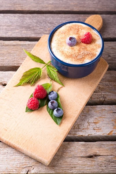 Few red and blue berries on chopping board with creamy dessert — Stock Photo, Image