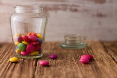 Çikolata smarties cam doz ve civarında ahşap tahta üzerinde renk