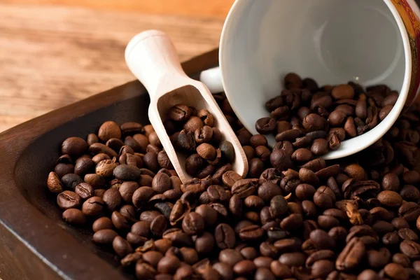 Koffie korrels op dienblad van donker hout en gemorste cup — Stockfoto