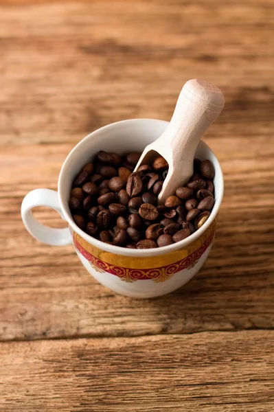 Bovenste deelvenster op cup met korrels van koffie en houten lepel — Stockfoto