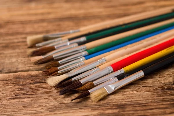 Collection of different paintbrushes on wooden board — Stock Photo, Image