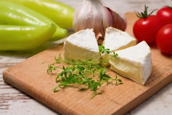 Three portions of camembert and cress on wooden board — Stock Photo, Image