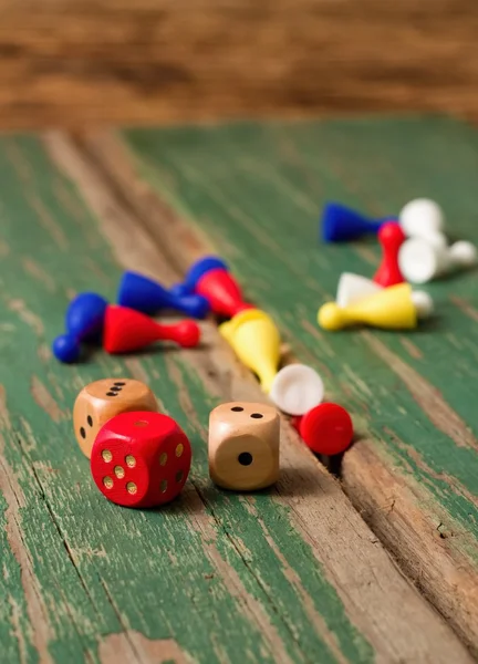 Three dices and color figurines on old wooden board — Stock Photo, Image
