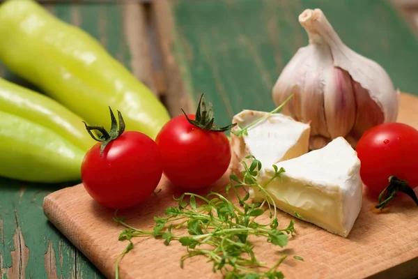 Agrião, Camembert e tomate em tábua de cortar — Fotografia de Stock