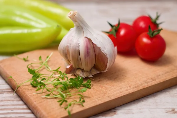 Cabeza de ajo en tabla de cortar con berros y tomates —  Fotos de Stock