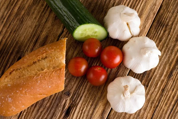 Quatro tomates entre pepino de alho e baguete — Fotografia de Stock