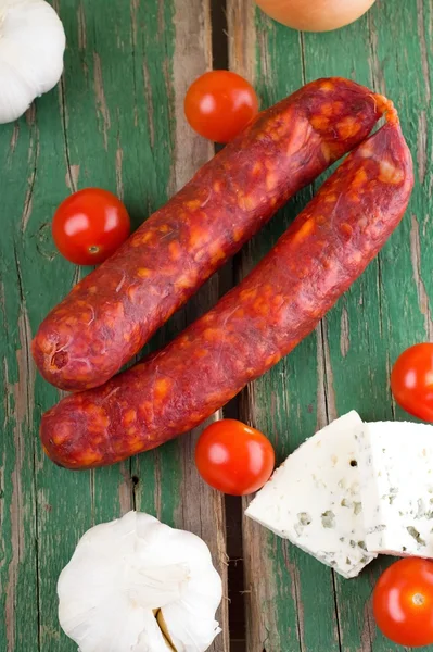 Bovenaanzicht op twee worstjes onder groente en kaas — Stockfoto
