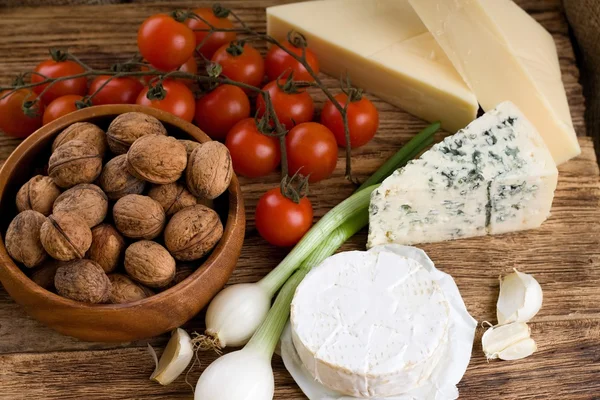 Três tipos de queijo e vários tipos de vegetais — Fotografia de Stock