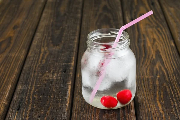 Дві вишні в холодному напої в банці з рожевою соломою — стокове фото