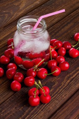 Pink straw in jar among heap of cherries