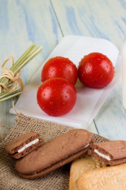 Three dewy tomatoes next to cereal biscuits clipart