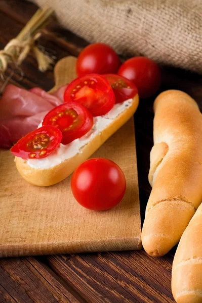 Tomate rojo cereza fresco entre rollos y baguette — Foto de Stock