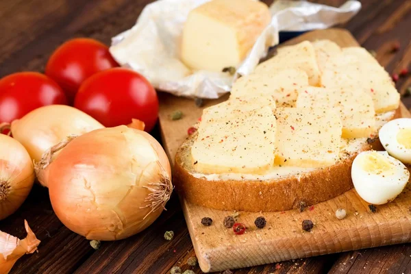 Piece of bread with ripened cheese on chopping board — Stock Photo, Image