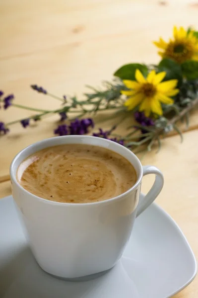 Tasse Kaffee mit Sahne vor Blumen — Stockfoto