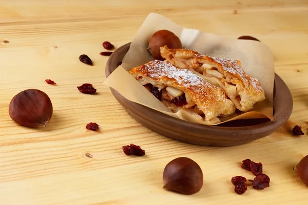 Chestnuts and raisins around apple strudel — Stock Photo, Image