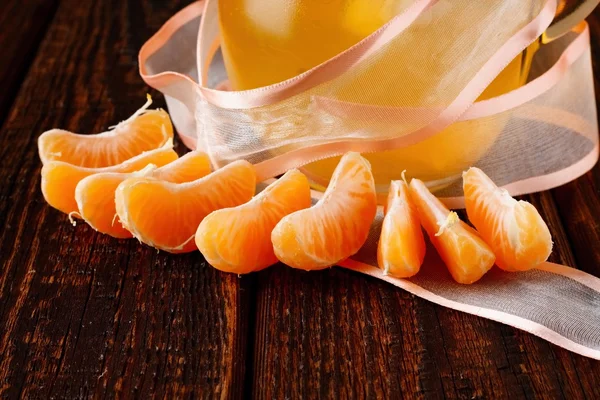Flera mandarin delar runt glasburk med juice — Stockfoto