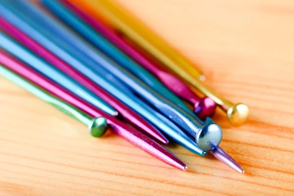 Several knitting needles on wooden board — Stock Photo, Image