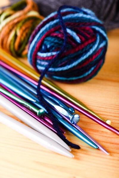 Несколько цветных вязальных иголок с шарами шерсти
