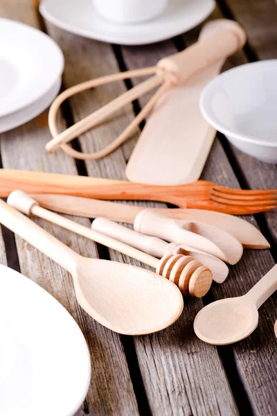 Various wooden spoons among white plates and bowls — Stock Photo, Image