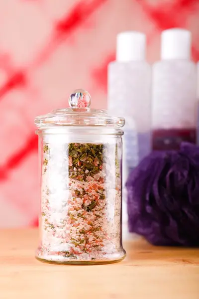 Glass jar with pink bath salt with herbs — Stock Photo, Image