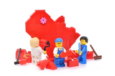 Sevgililer Günü 'ne editoryal çizim. Minyatür işçi figürleri tarafından plastik yapı taşlarından yapılmış kırmızı lego kalbi.. 