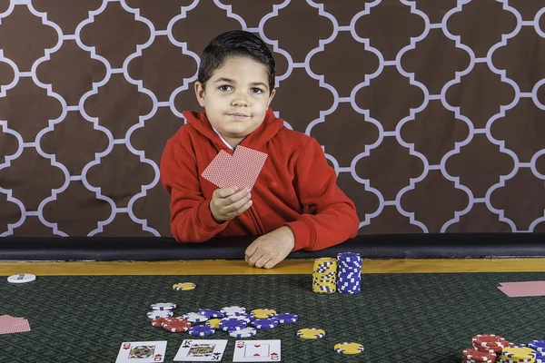 Ein kleiner Junge pokert an einem Tisch — Stockfoto