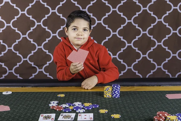 En ung pojke spelar poker på ett bord Royaltyfria Stockbilder