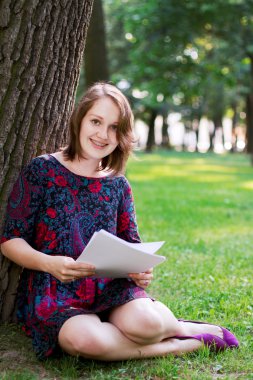 bir ağacın altında oturan bir genç bayan