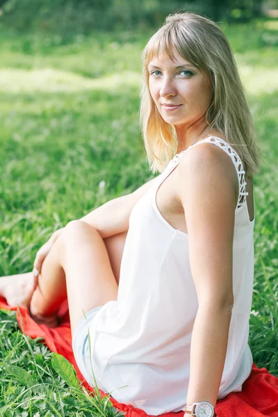 Jonge vrouw zit op groen gras — Stockfoto